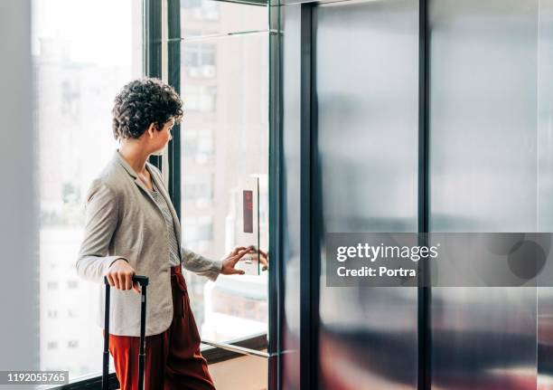 businesswoman waiting for elevator in hotel - elevator doors stock pictures, royalty-free photos & images