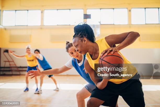 mujeres jugando baloncesto en el interior - baloncesto femenino fotografías e imágenes de stock