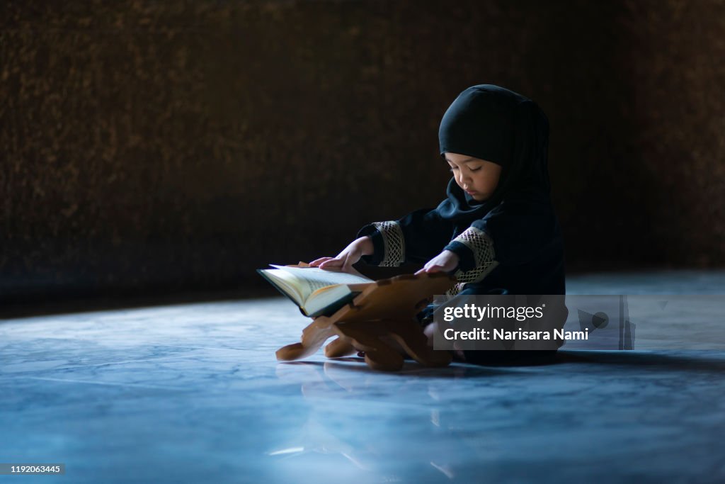 Asian Indonesian Muslim kid is reading the Quran. The Quran is indicated as the guided book for all Muslim and it is direction to be on the heaven of God.Mosque,Islam,religion and knowledge concept.