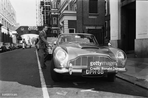 Anthony Armstrong-Jones, Lord Snowdon opens the door of his new Aston Martin DB5 coupe car parked on a street in London, 2nd July 1965.