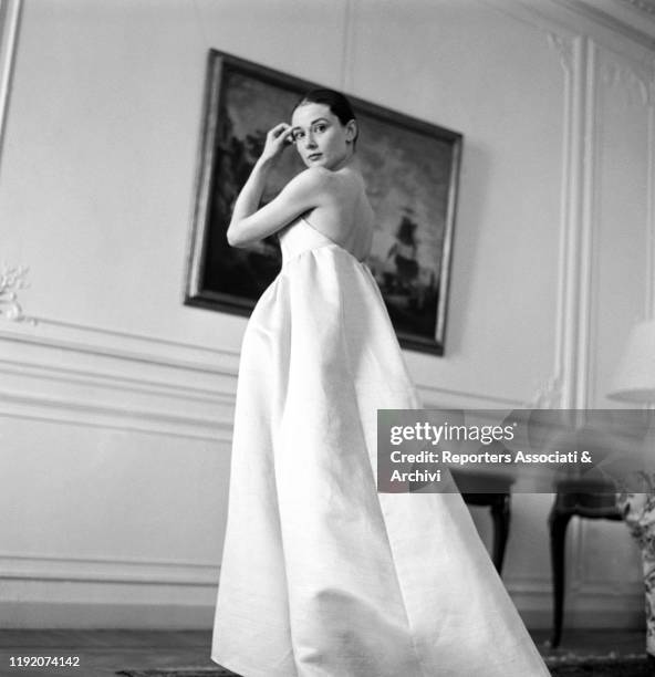 British actress Audrey Hepburn posing with a dress by French stylist Hubert de Givenchy. Paris, 1958