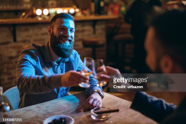 knappe bebaarde mannen drinken whiskey - whisky bar stockfoto's en -beelden
