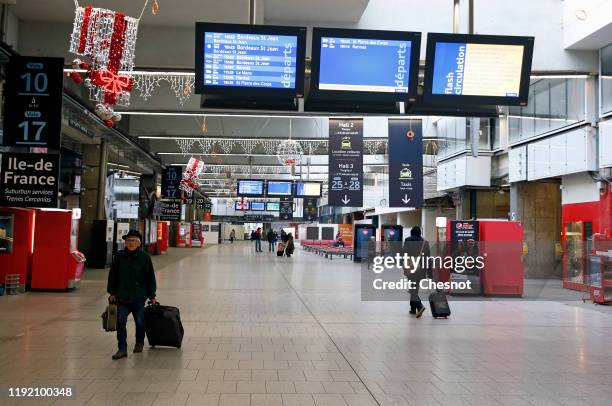 Passenger walks by information screens displaying a message warning passengers about a national strike at Gare Montparnasse train station in Paris...