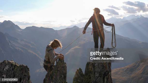 vrouwelijke bergbeklimmer vervormt up mountain ridge - berg klimmen team stockfoto's en -beelden