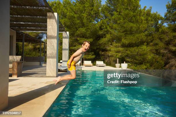 young boy jumps into pool - baleric islands stock pictures, royalty-free photos & images