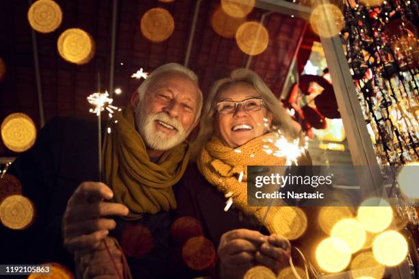 romantic senior couple with sparklers during christmas holidays - christmas elderly stock pictures, royalty-free photos & images