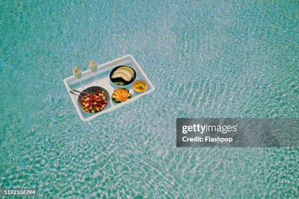 a breakfast tray floats across a pool (wide) - comida flores fotografías e imágenes de stock