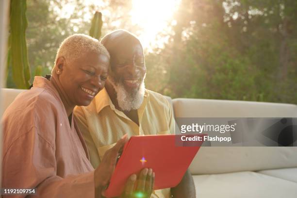 older couple laugh with a digital tablet - hot spanish women stock pictures, royalty-free photos & images