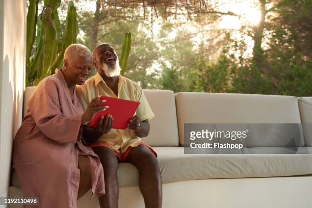 older couple laugh with a digital tablet - bonding stock pictures, royalty-free photos & images