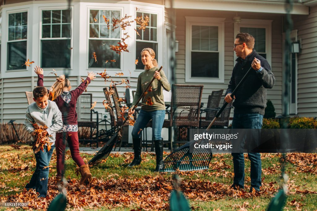 Cheerful Family Raking Autumn Leaves