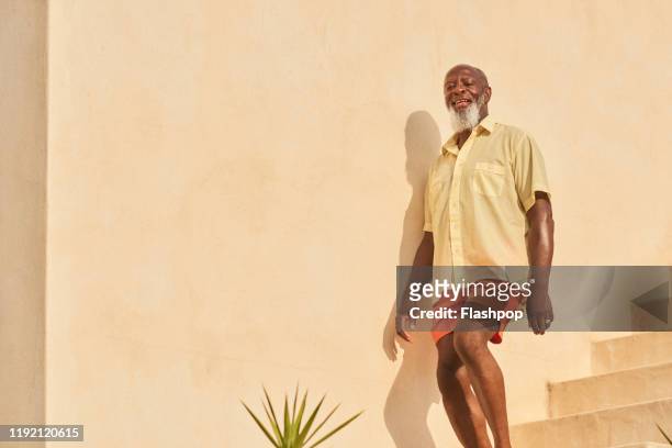 mature man walks down stairs - black shorts photos et images de collection