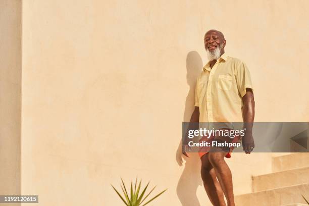 mature man walks down stairs - black shorts stockfoto's en -beelden