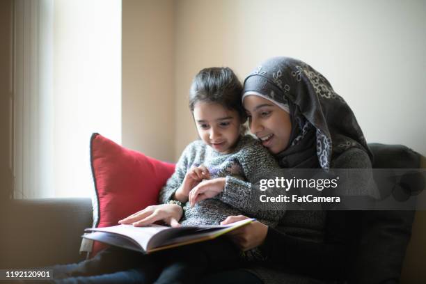 muslim girl reading to her sister stock photo - refugiado imagens e fotografias de stock