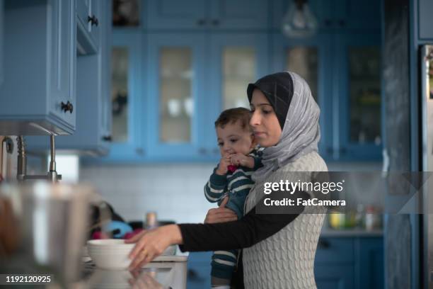 moslim moeder en werken in de keuken met baby stock photo - muslim boy stockfoto's en -beelden