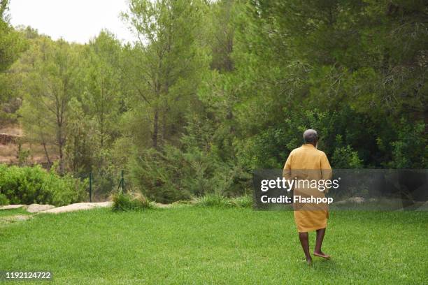 mature man walks across lawn. - robe stock pictures, royalty-free photos & images