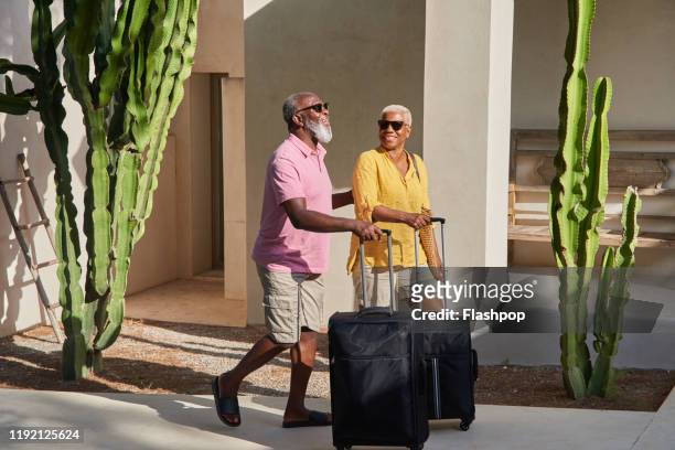 a mature couple arrive at a holiday villa - reisbestemmingen stockfoto's en -beelden