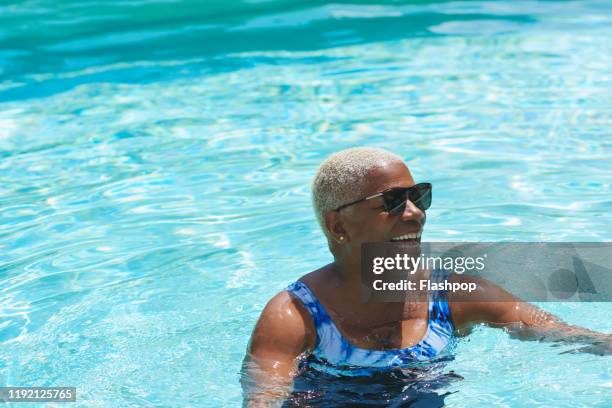 mature woman relaxing in swimming pool - mature women swimming stock pictures, royalty-free photos & images