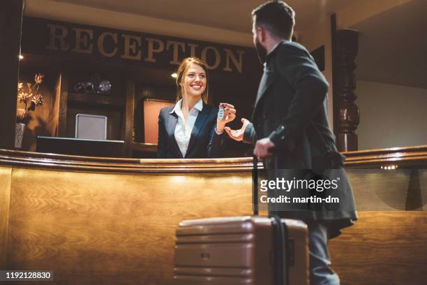 receptionist die sleutels geeft aan hotelgasten - reception stockfoto's en -beelden
