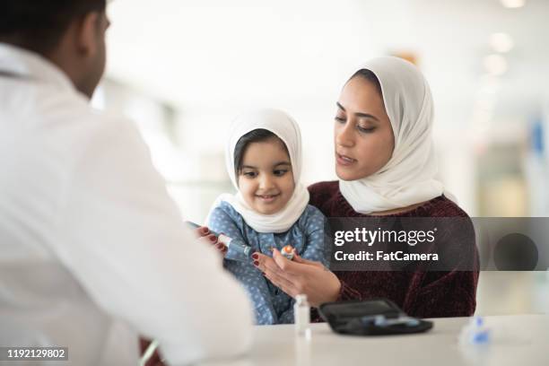doctor explaining how to inject insulin to a mother and daughter stock photo - afghan ethnicity imagens e fotografias de stock
