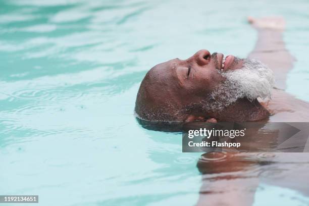 a mature man relaxes in a pool - morning swim stockfoto's en -beelden