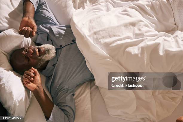 mature man wakes in bed - black man sleeping in bed - fotografias e filmes do acervo