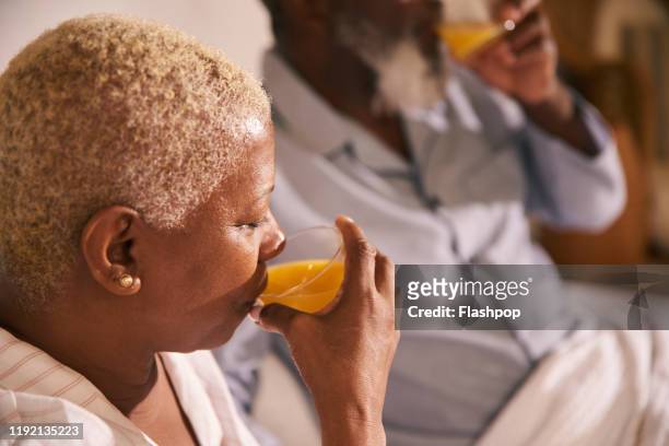 mature woman drinks orange juice - orange juice stock pictures, royalty-free photos & images
