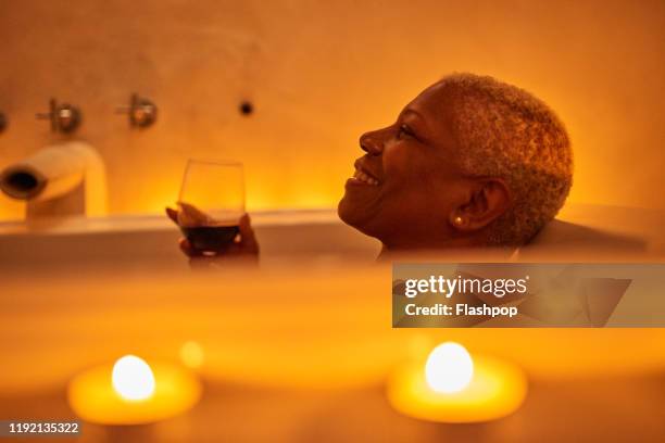 mature woman relaxes in bath - drinking alcohol at home stock pictures, royalty-free photos & images