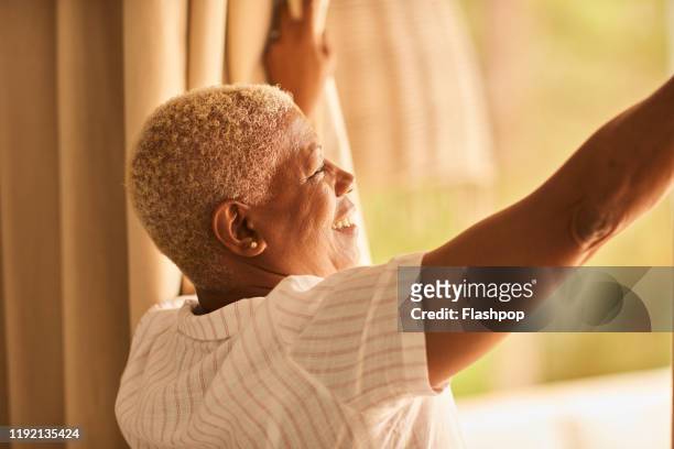 mature woman looks outside - mattina foto e immagini stock