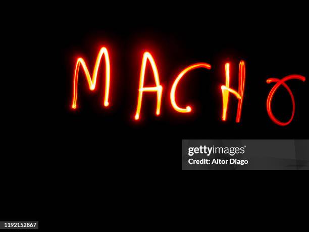 macho written in spanish which means male in the sense of "old masculinity stereotype" with red light on a black background - macho photos et images de collection