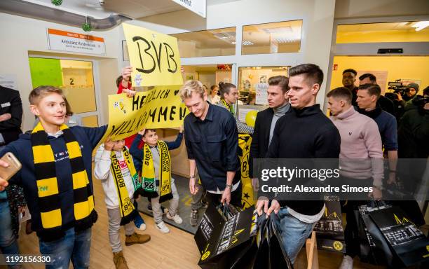 Julian Brandt, Lukasz Piszczek and Julian Weigl of Borussia Dortmund are greeted by children during the annual visit at the Children's Hospital on...