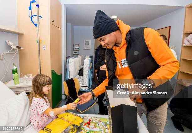 Manuel Akanji of Borussia Dortmund hands over gifts to a kid during the annual visit at the Children's Hospital on December 04, 2019 in Dortmund,...