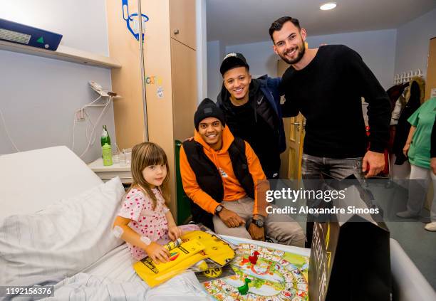 Manuel Akanji, Jadon Sancho and goalkeeper Eric Oelschlaegel of Borussia Dortmund pose with a kid during the annual visit at the Children's Hospital...