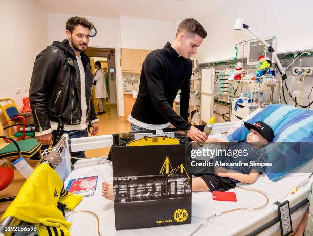 Goalkeeper Roman Buerki and Julian Weigl of Borussia Dortmund hand over gifts to a kid during the annual visit at the Children's Hospital on December...