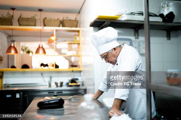 een bezorgde senior chef-kok in de keuken teller - problemen stockfoto's en -beelden