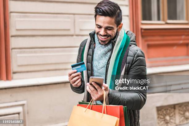 portrait of a young man using credit card - young men shopping stock pictures, royalty-free photos & images