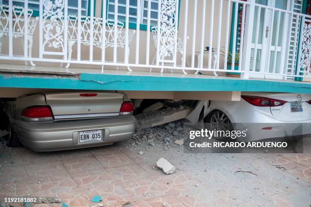 Cars are seen under a collapsed house damaged by a 5.8 earthquake in Guanica, Puerto Rico on January 6, 2020. 8-magnitude earthquake shook Puerto...