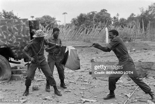 Three soldiers of the FNLA tear up the MPLA flag, on August 6, 1975 in caxito during the Angolan Civil War.