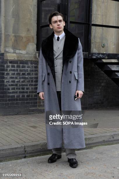 Mathias le Fevre wearing a double breast grey suit and overcoat attends the London Fashion Week Men's Day two Street Style.