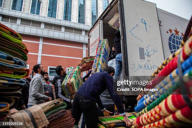 Group of men load sacks of items in a transport truck. A team of Syrian refugee youth in Gaziantep, Turkey, launched a charity campaign to collect...