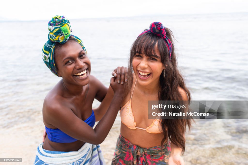 Two young women friends at the beach laughing together