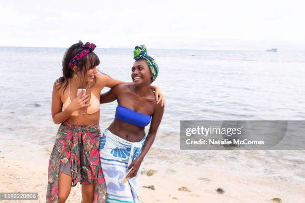 two young women friends at the beach laughing together - sarong imagens e fotografias de stock