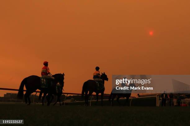 Riders return to scale after race 6 as smoke from the Sydney bushfires covers the track during Sydney Twilight Racing at Royal Randwick Racecourse on...