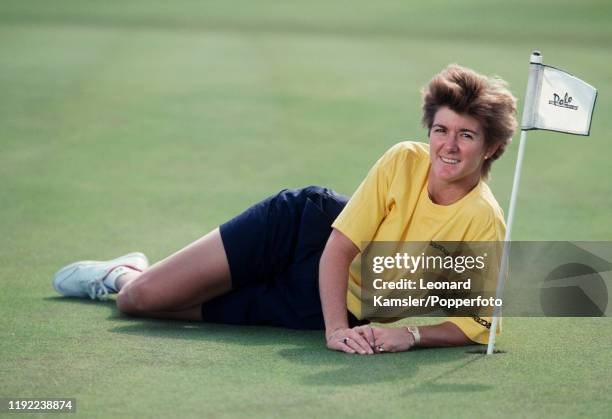 American golfer Beth Daniel lying on a putting green next to a mini-flag, circa 1990.