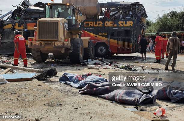 Firefighters, workers and locals recover corpses from a double-decker bus after it crashed with parked cars on the Pan American Highway in the...