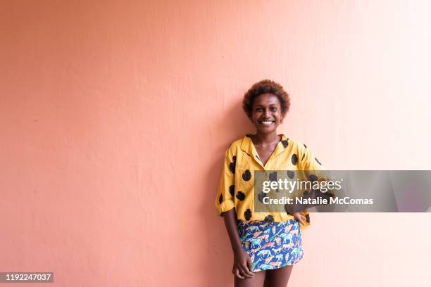 one young woman in front of pink wall smiling - honiara stock pictures, royalty-free photos & images