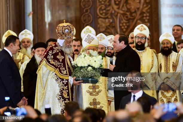 Egyptian President Abdel Fattah al-Sisi present flowers to Coptic Pope Tawadros II during a Christmas Eve mass at the Nativity of Christ Cathedral in...