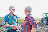 Farmer shaking hands while standing in field