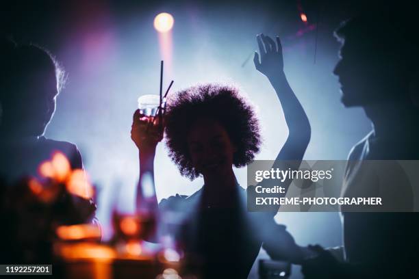 silueta de una chica con un afro bailando con un cóctel en la mano en un club nocturno - afro fotografías e imágenes de stock