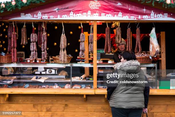 frau kauft salami-wurst vom fleischstand auf lebensmittelmarkt - sibiu stock-fotos und bilder