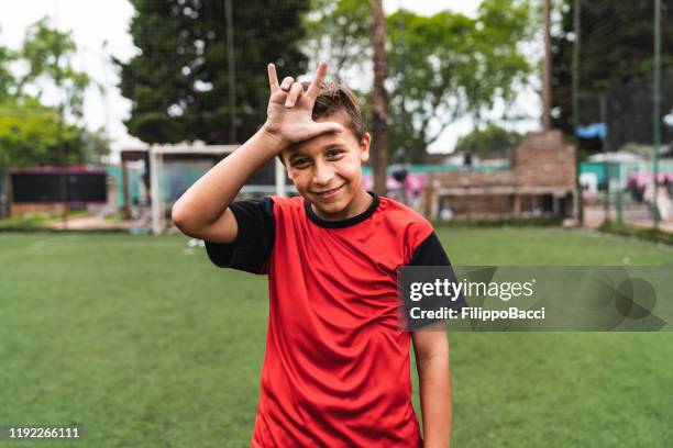 soccer player boy doing hand gesture standing on a soccer field - horn sign stock pictures, royalty-free photos & images